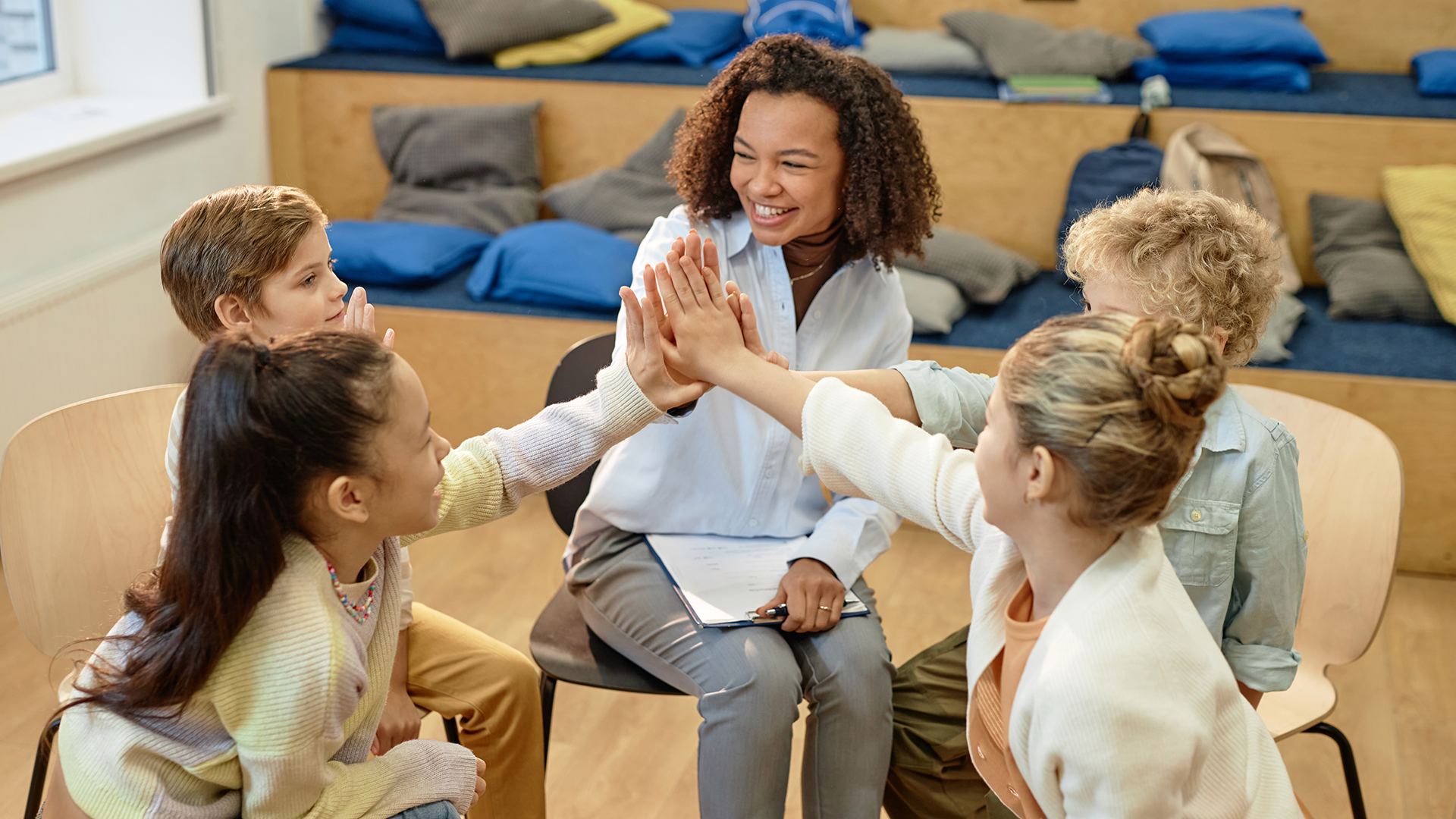 Image of a group of excited children high five with female